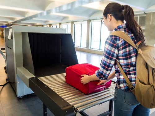Woman putting her bag through airport security check