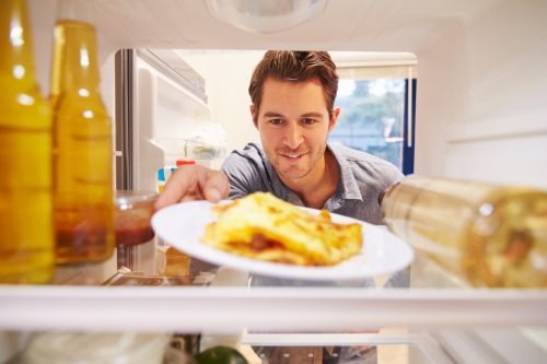 man putting plate of eggs into the fridge