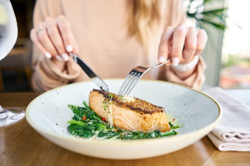 Hands of woman eating fish