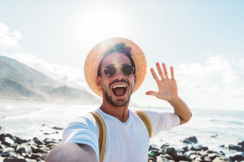 Young man with backpack taking selfie portrait outside