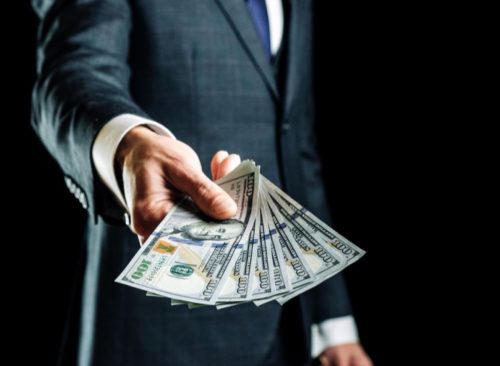 Businessman holding hundreds of dollars in cash.