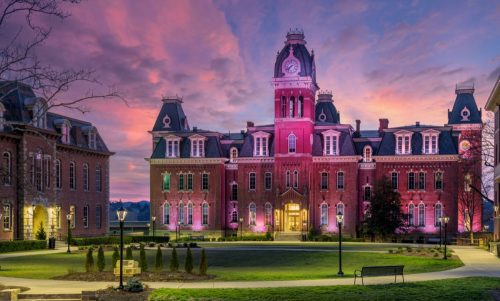Dramatic image of Woodburn Hall at West Virginia University or WVU in Morgantown WV as the sun sets behind the illuminated historic building.