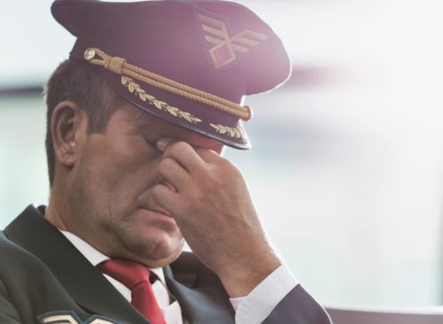 Portrait of sleepy and overworked pilot sitting in airport