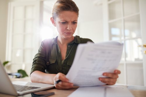 Portrait of young female sitting at table reading documents.