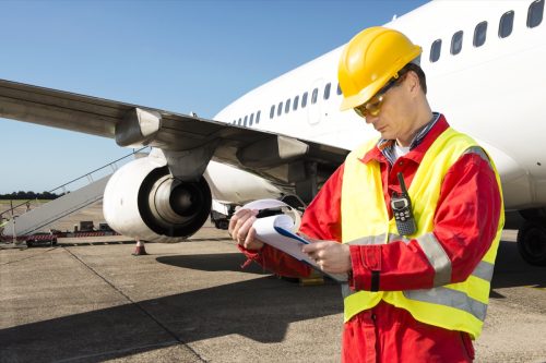 Aircraft engineer with a checklist of several pages on a clipboard.