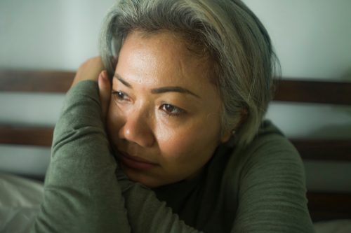 mature lady crisis - attractive middle aged woman with grey hair sad and depressed in bed feeling scared and lonely thinking worried about covid-19 virus pandemic during home lockdown