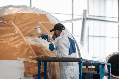 Worker painting a plane inside the big hangar.