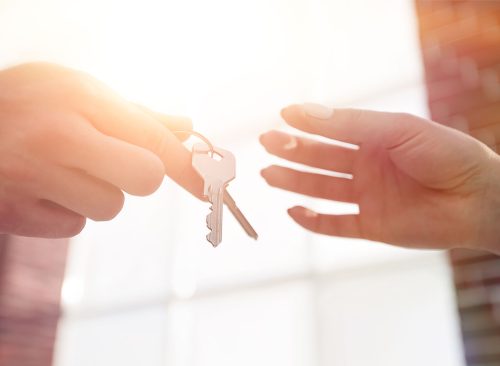 Cropped image of estate agent giving house keys to man in office