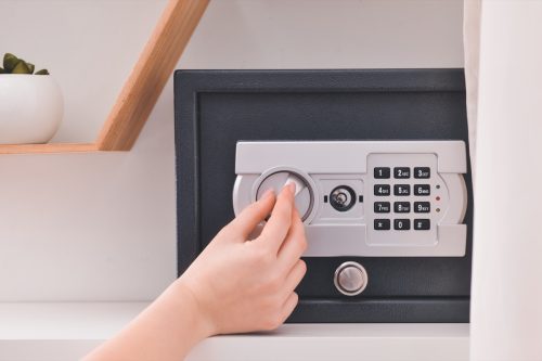 Woman opening modern safe indoors.