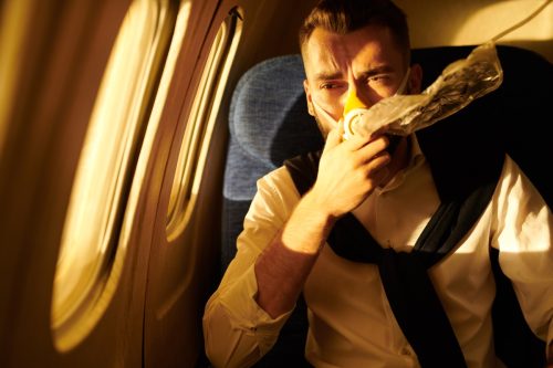 Portrait of a young man wearing oxygen mask in plane, copy pace