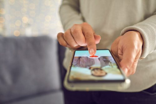 Adult woman pressing red heart like button below man's profile photo on dating app