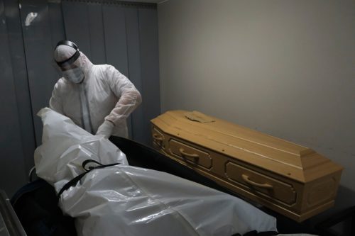 Mortuary workers put the body inside a coffin at funeral home.