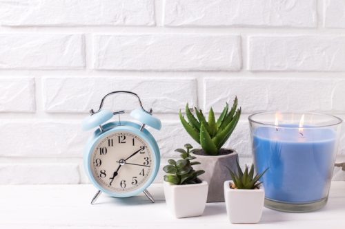 blue alarm clock and succulents and candle on nightstand