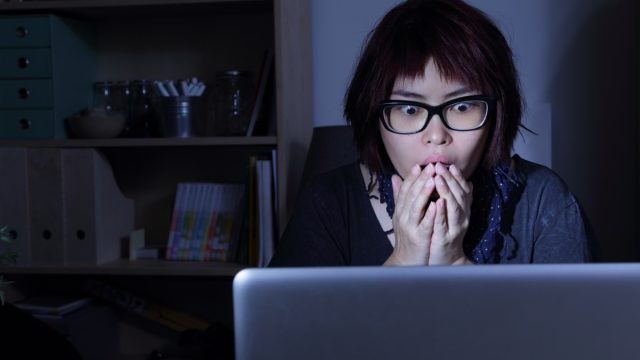 woman looks at laptop in shock