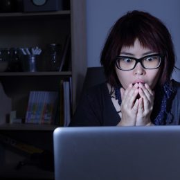 woman looks at laptop in shock