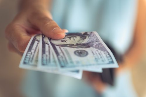 hand holding hundred dollar bills of US currency