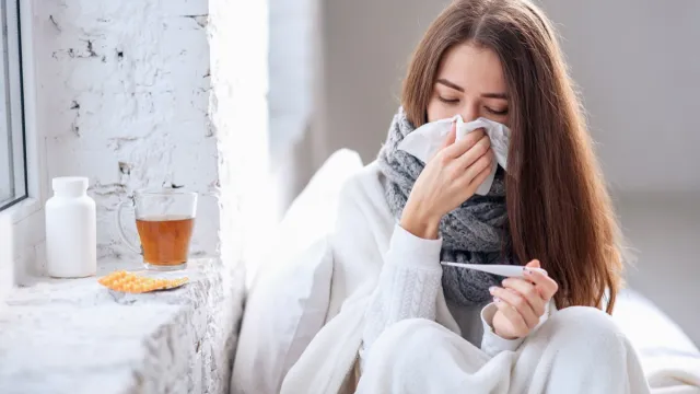 Woman with flu taking temperature