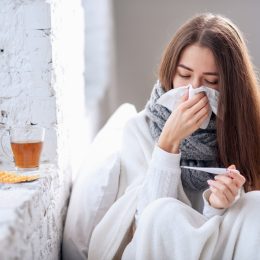 Woman with flu taking temperature