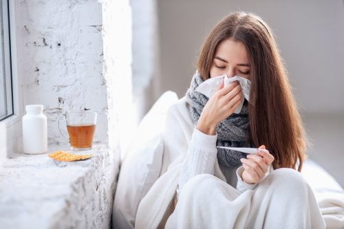 Woman with flu taking temperature