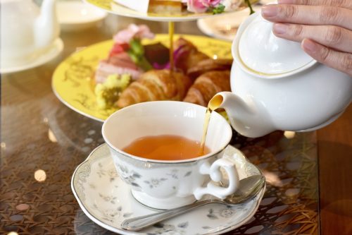 Pouring tea from vintage teapot to the cup.