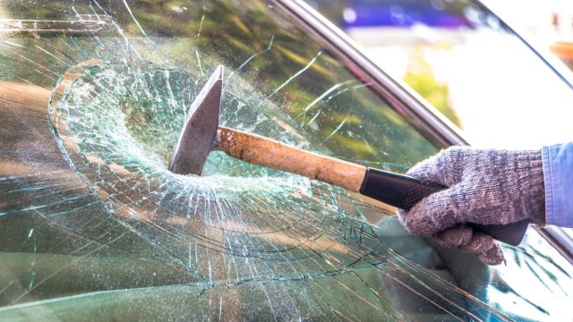 Technician use hammer for Broken car windshield. Selective focus.