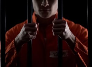 Inmate holding prison bars.