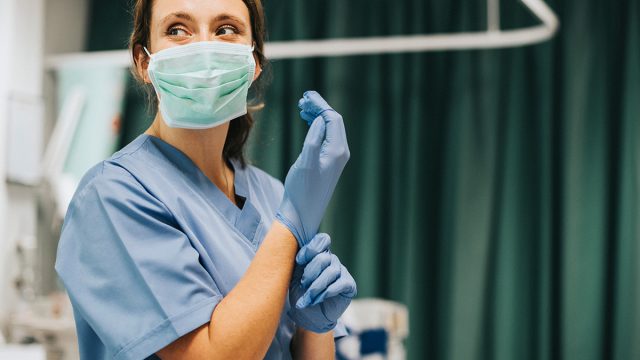 Female,Nurse,With,A,Mask,Putting,On,Gloves