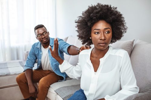 Woman pushing man aside during argument on the couch