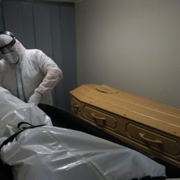 Mortuary workers put the body inside a coffin at funeral home.