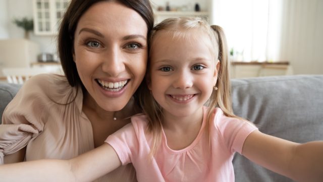 Smiling,Young,Mother,And,Small,Preschooler,Daughter,Look,At,Camera