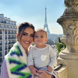 Influencer Poses with Son on Edge of Balcony