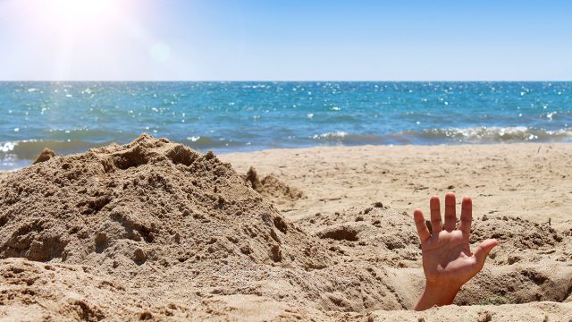 Human,Hand,Out,Of,The,Hole,On,The,Sandy,Beach