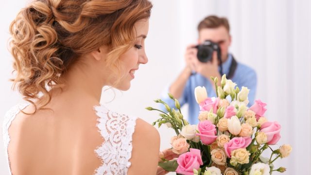 Wedding photographer taking photo of bride in studio.
