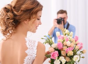 Wedding photographer taking photo of bride in studio.