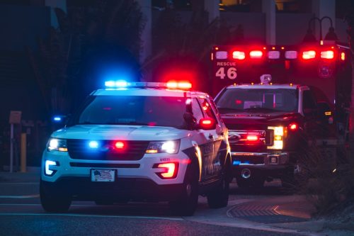 American Police Car and Emergency truck with Blue and red lights. US Paramedic Fire Rescue resuscitation help. Investigation Crime, murder, theft, police arrest. Photo has a dramatic toning.