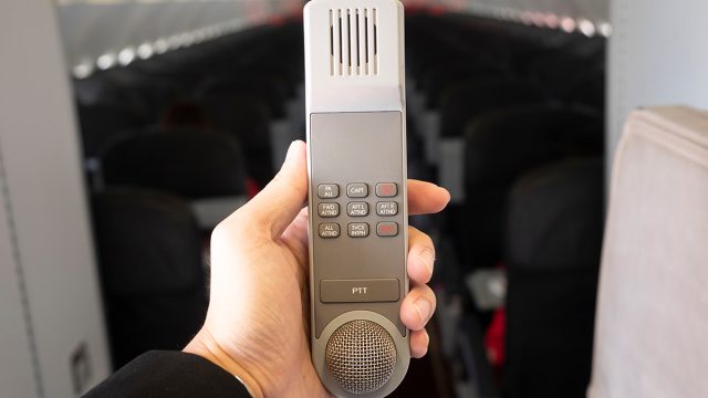 Male,Cabin,Crew,Holding,Interphone,In,Aircraft,Cabin.,Cabin,Intercom