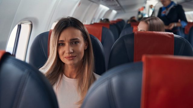 Sad woman sitting on a plane near window