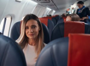 Sad woman sitting on a plane near window
