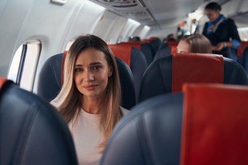 Sad woman sitting on a plane near window