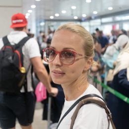 Young blond caucasian woman waiting in long line at security check at the departure airport terminal. Lady standing in long queue at airport before boarding a plane.