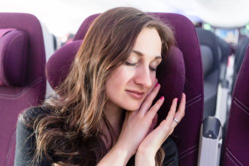 Woman traveler having a nap in airplane cabin.