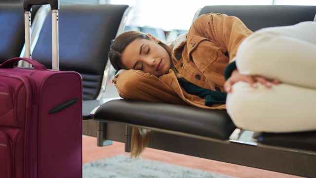 Tired, sleeping and woman at airport, waiting and bench for travel, international transport and flight delay
