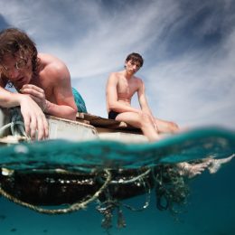 Two men floating in a sea with sad faces