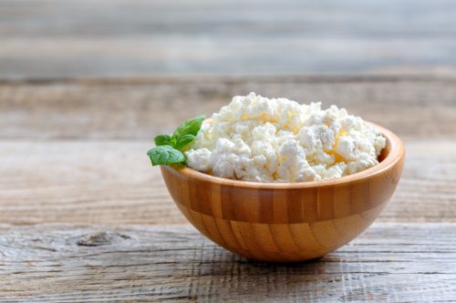 Homemade cottage cheese in a bowl on old wooden table.