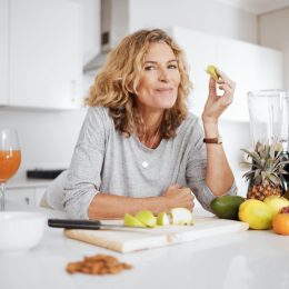 Portrait, fruit salad and apple with a senior woman in the kitchen