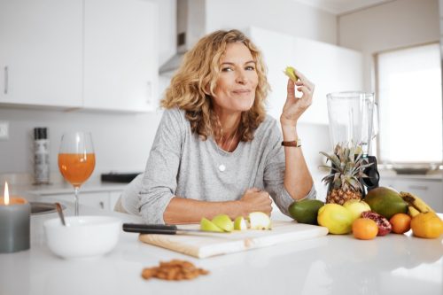 Portrait, fruit salad and apple with a senior woman in the kitchen