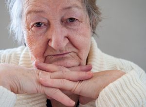 Elderly woman with beautiful wrinkled face is holding pills in her hands to choose medicines. Selective focus depth of field