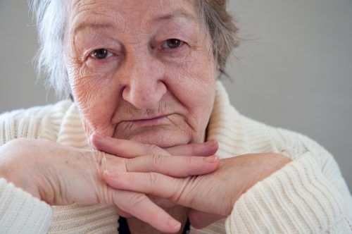 Elderly woman with beautiful wrinkled face is holding pills in her hands to choose medicines. Selective focus depth of field