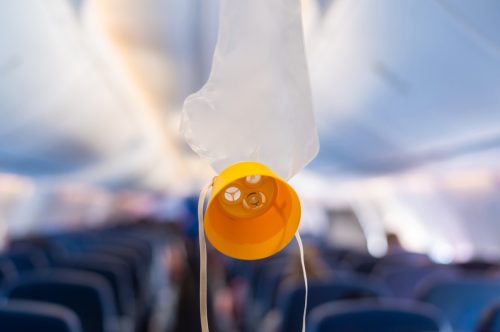 Oxygen mask drop from the ceiling compartment on airplane.