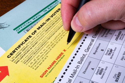  Hand prepares to sign signature on official mail-in ballot for 2020 US General Election.